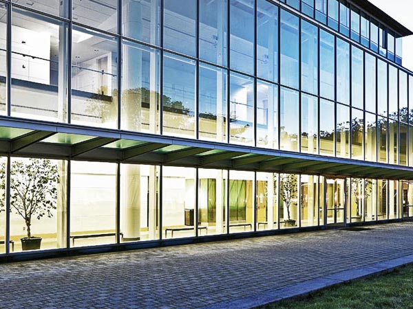 Modern building with glass exterior and illuminated interiors at night.