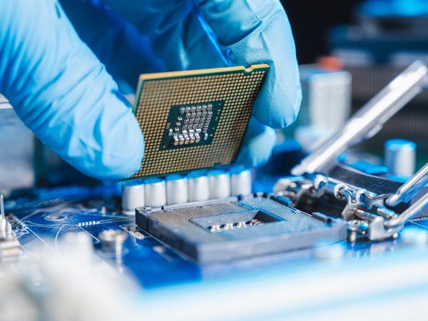 Gloved hand installing a computer processor onto a motherboard.