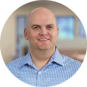jim wible wearing a white plaid shirt standing indoors in an office setting